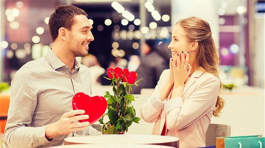 Guy giving chocolates and roses to his girlfriend on Valentine's day 
